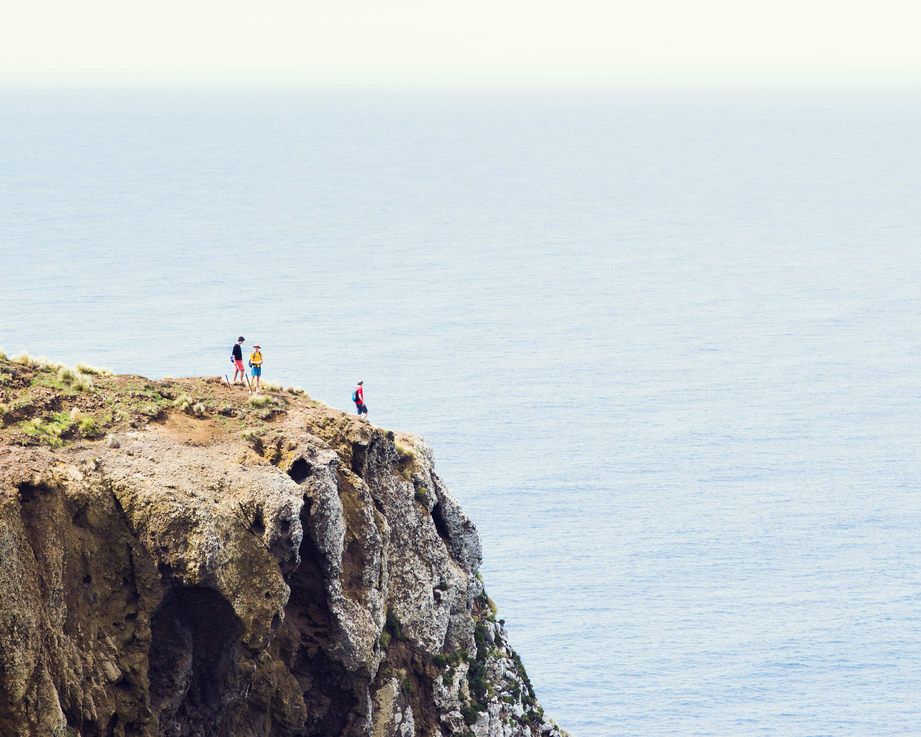 A few tiny figures exploring the end of a cliff over an endless sea.