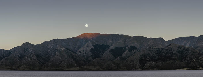 A wide panorama of the moon over a mountain ridge, and Lake Wanaka.