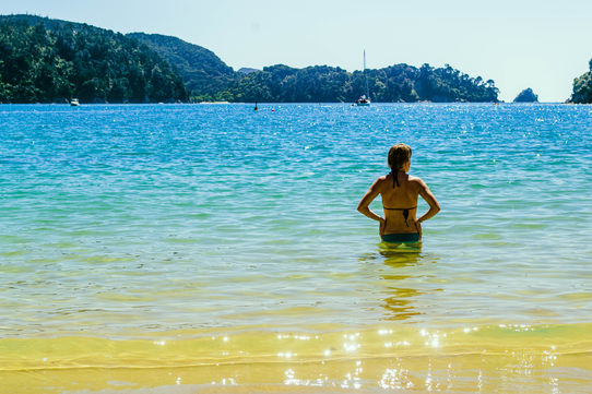 Britt standing waist deep in dramatically yellow-turquoise-blue beach water.