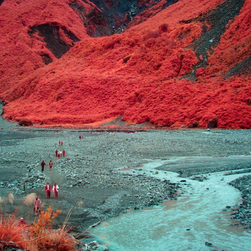 A line of people hiking through a glacial valley. This one looks especially other-worldly.