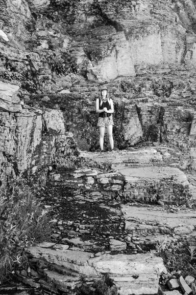 A woman (Britt), small, standing in front of a big granite rock face with lots of texture