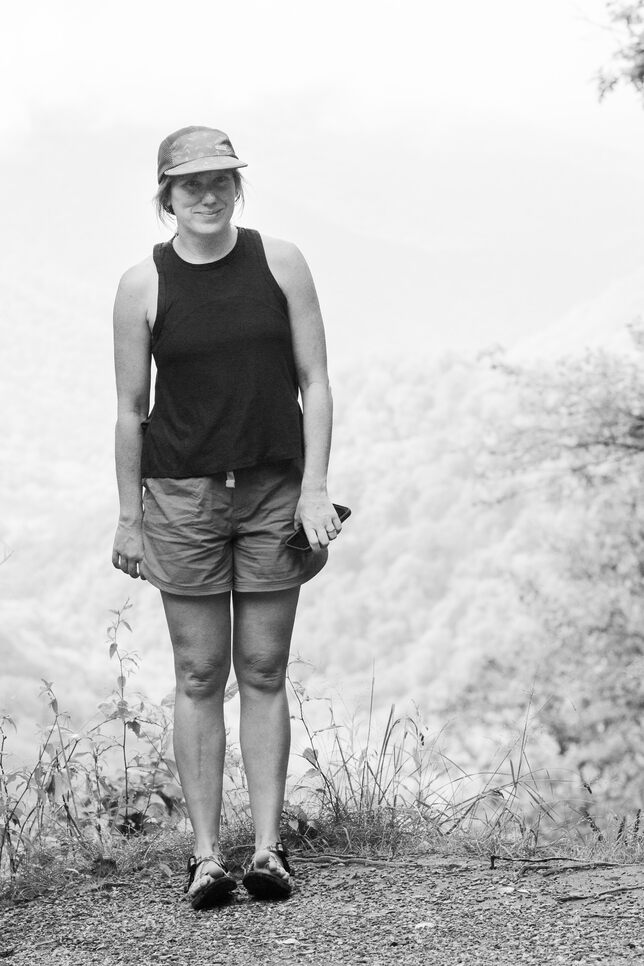 Britt standing and smiling for a portrait, smiling, toes pointed to the sky, curled.